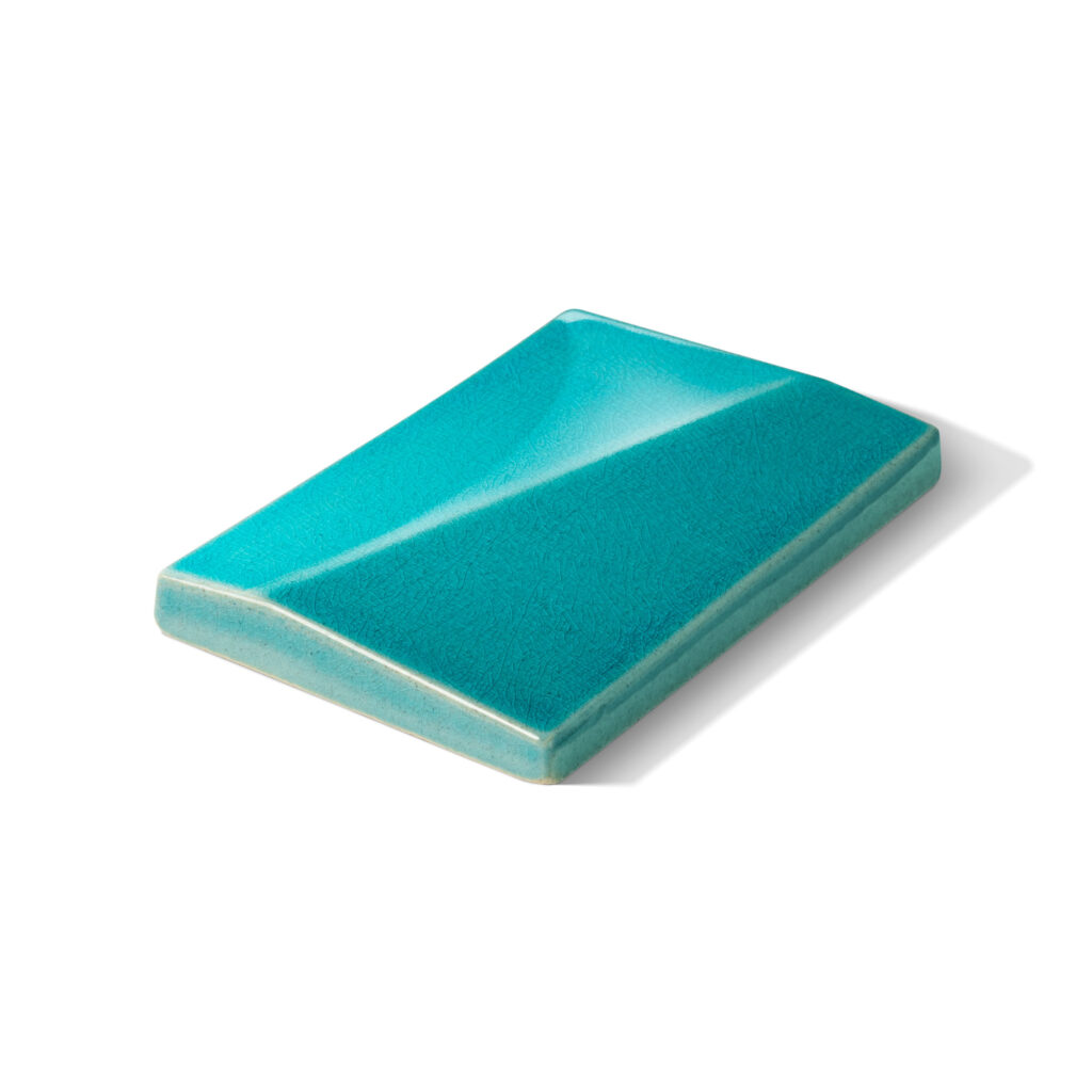Fliese DREIKLANG in der Farbe Turquoise-craquele. Das Bild zeigt eine einzelne DREIKLANG-Fliese in einem tuerkisen Farbton mit Craquele-Effekt. Die Datei ist ein Foto im JPEG-Format.