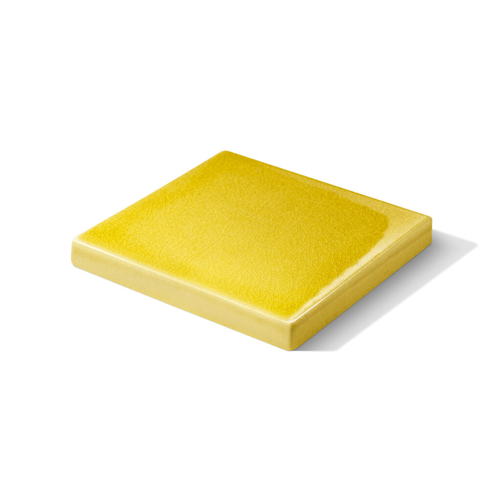 Fliese PLAETTLI in der Farbe Gelb Craquelé. Das Bild zeigt eine einzelne LIMMAT-Fliese in einem gelben Farbton. Die Datei ist ein Foto im JPEG-Format.